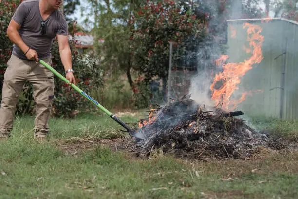 Photo of Man tending to fire controlled burn off of garden waste