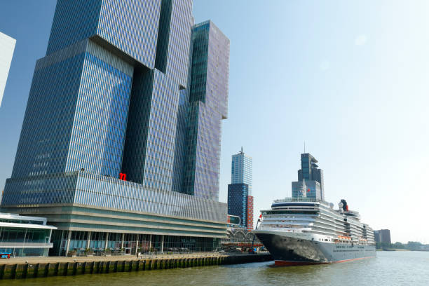 Rotterdam, Netherlands - June 26, 2019: The new harbor district of Rotterdam (Kop van Zuid) located on the south bank of the Nieuwe Maas, opposite to the city center of Rotterdam. View from the Erasmus Bridge. Cruise ship Queen Victoria anchors at the Kop van Zuid pier.