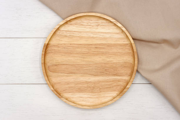 istock Empty round wooden plate with beige tablecloth on white wooden table. 1159397443