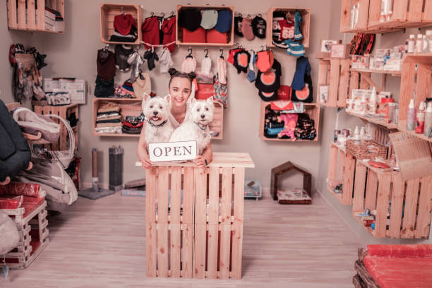 Shop for pets. Dark-haired beautiful young woman smiling while opening shop for pets
