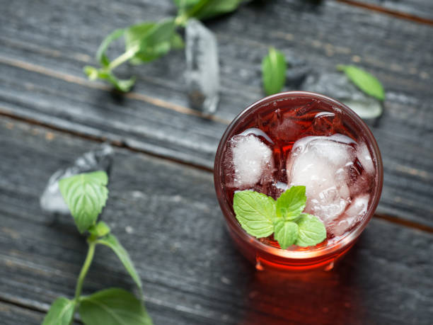 Red cocktail with ice and mint close-up