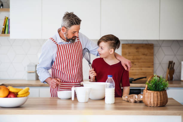 istock Mature father with small son indoors in kitchen, making pancakes. 1159401935