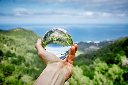 Hand holds a crystal ball you see a landscape in and around the glass ball First Person View