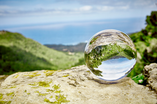 Landscape seen through a great crystal ball-one sees a sea and a green valley. First Person View