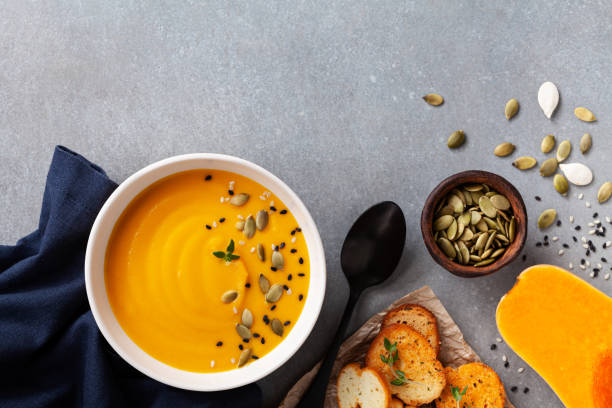 Healthy autumn pumpkin cream soup in bowl served with seeds and crouton on stone table top view. Healthy autumn pumpkin cream soup in bowl served with seeds and crouton on stone table top view. Copy space for text. squash soup stock pictures, royalty-free photos & images