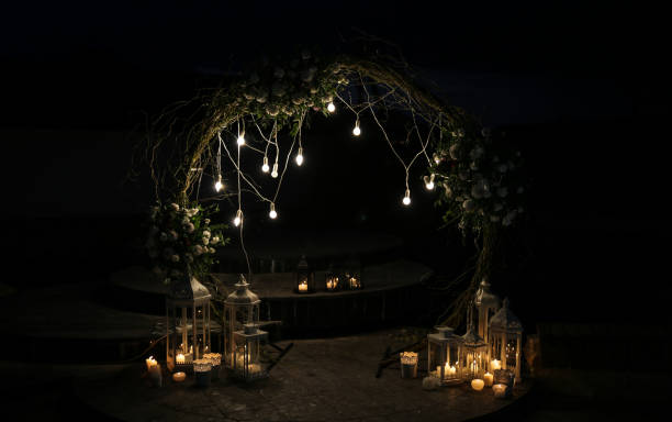 istock White flowers arch at the wedding ceremony. Outdoors decoration. Romantic rustic style. Lamps lights in the evening. 1159405917
