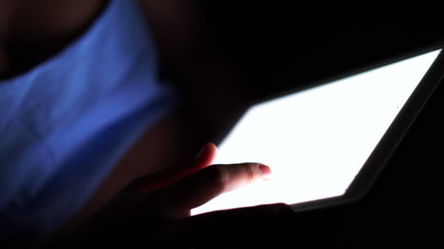 Woman using tablet in the dark.
