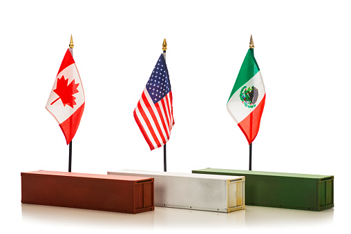 Canadian, American and Mexican flags behind shipping containers, one red, one white and one green, against a white background.  Concept of international trade and tariffs.