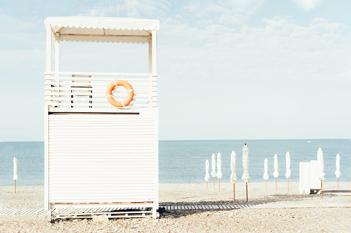 A life-saving white wooden house-tower on the seashore, seascape, the mood of hot summer holidays and vacations, pastel oenki and bright sunny morning light.