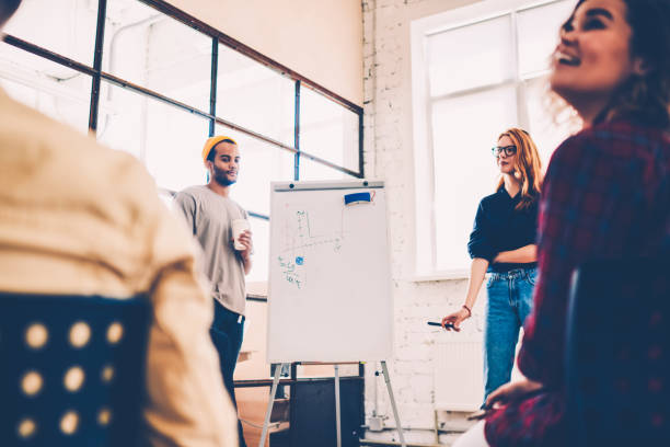 istock Male and female colleagues standing near flip chart explaining common project strategy during workshop, young students making speech for group using board for illustration share ideas and opinions 1159410312