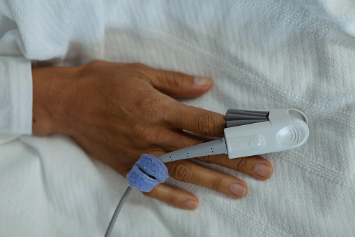 Close-up of pulse oximetry on mixed race female patient hand in the ward at hospital