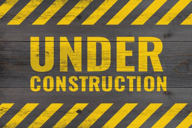 Photo of under construction warning message painted on aged wooden planks