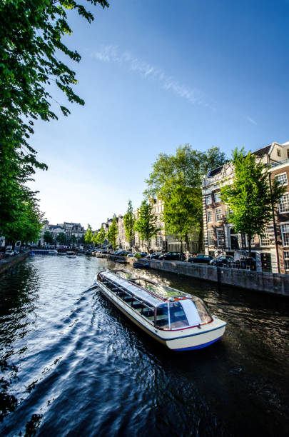 bateau de croisière dans le canal d'amsterdam - magere brug photos et images de collection