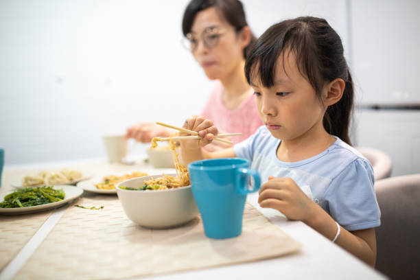 istock Hungry Taiwanese girl using chopsticks to eat 1159419237