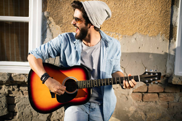 istock Handsome man playing guitar on the street on summer day 1159419723