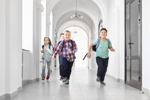 istock Happy pupils running forward on corridor of school. 1159419929