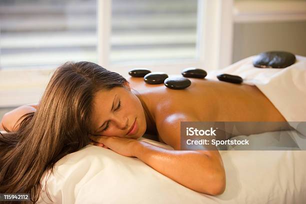 Woman Lying Down Peacefully On A Table With Massage Stones Stock Photo - Download Image Now