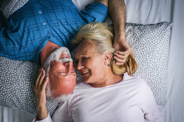 old senior couple are kissing in bed - men sensuality photography high angle view imagens e fotografias de stock