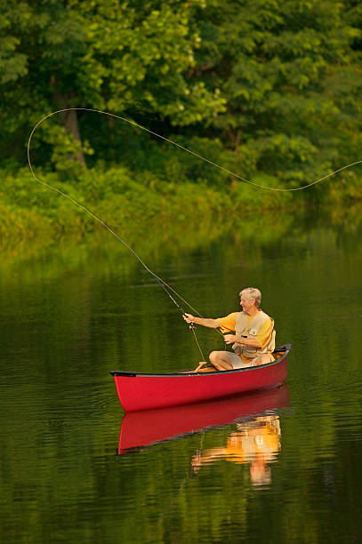 Senior Man Fly Fishing From Canoe