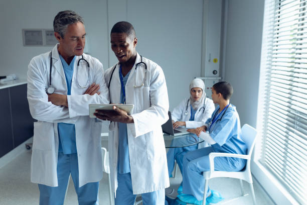 istock Male doctors discussing over digital tablet and female doctors using laptop 1159424518