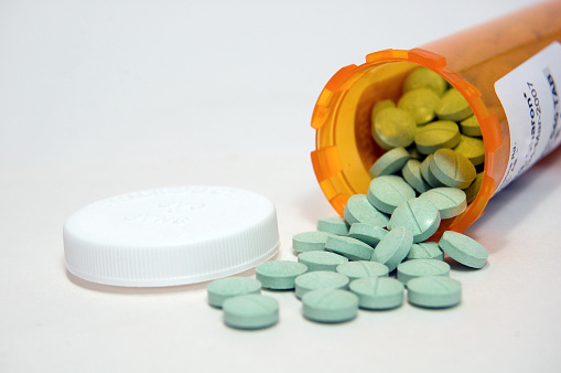 Green tablet, pills, spilled from a prescription bottle ... on white
