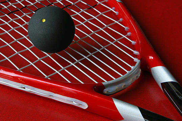 Close up squash racket and ball  Close-up of a squash racket and a ball on a red background. racketball stock pictures, royalty-free photos & images