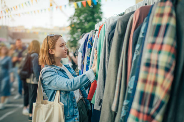 joven eligiendo ropa en un mercado de segunda mano en verano, concepto de cero residuos - vestimenta fotografías e imágenes de stock