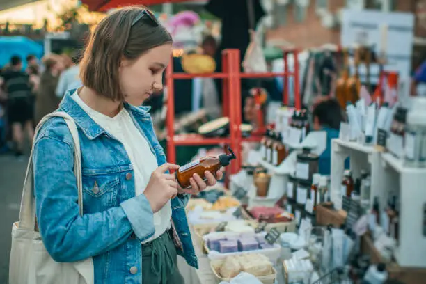 Photo of Young girl exploring organic body care goods at an open-air market with zero waste concept