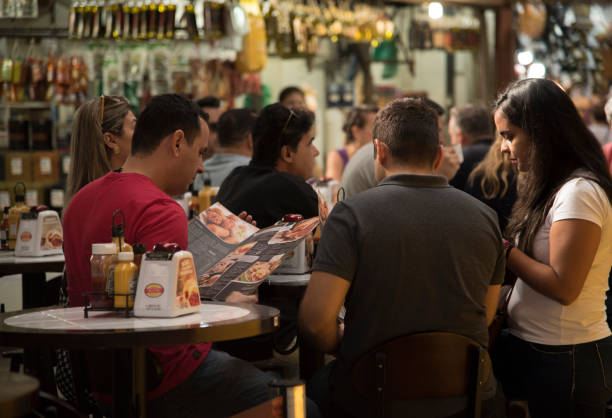 Santa Cruz, Tenerife, Spain, Europe - December 20th 2025: A group of people in a festive mood waits for their food and drinks in front of a fast‑food truck at the annual Christmas market. The scene documents everyday activity at the seasonal event, showing visitors gathering around a mobile food stall amid holiday decorations and the lively market atmosphere.