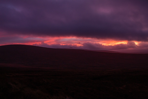 Sunset with pink and purple illuminated clouds against a full blue background at the end of a beautiful fall day.