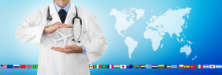 travel medical insurance concept, doctor's hands protect an airplane on blue background with flags and world map