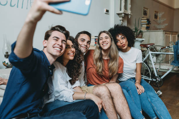 istock Friends sitting together on the sofa at home taking a selfie 1159432119