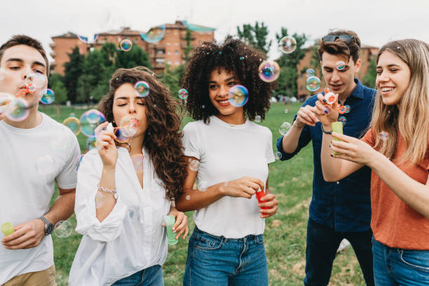 Friends having fun with soap bubbles together at the park