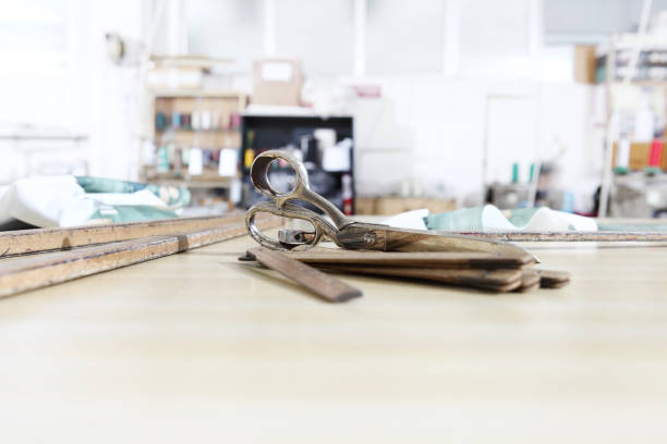 Close-up of woman using scissors to cut fabric from roll in costume designer workshop.