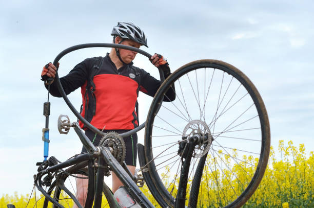 a man repairing a Bicycle in a field, a puncture of a Bicycle camera on the way stock photo