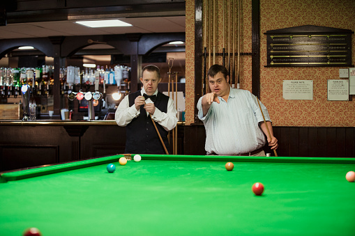 Man with Down syndrome helps his friend during a snooker game.