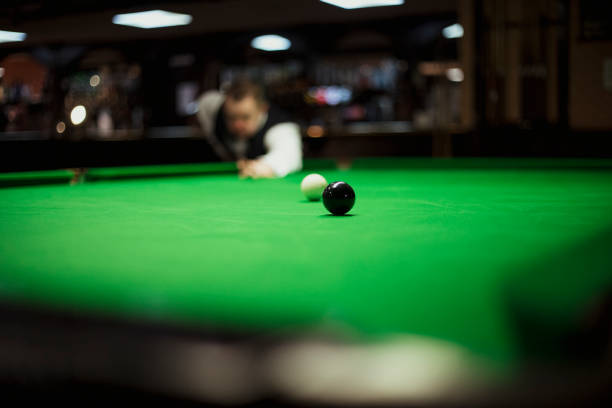 Snooker player with Down syndrome poised to hit the cue ball in order to pot the black ball.