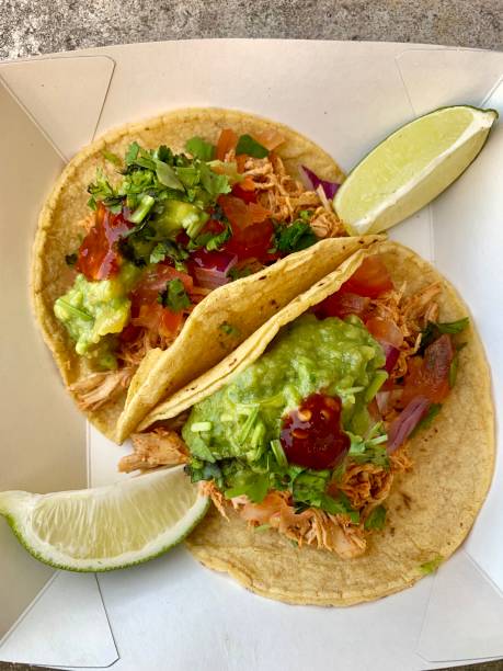 istock Two chicken tacos with guacamole, hot sauce, tomatoes and lime. 1159435625