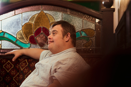 Happy man with Down syndrome sitting in a pub with his friends.