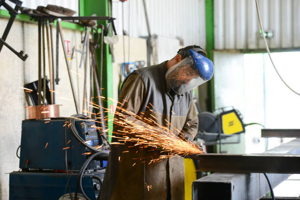 istock handsome man workshop grinding iron spark fire hot steel with power tool and protective gear 1159436899
