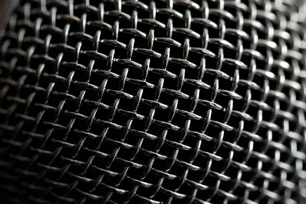 Steel grille background. Close-up shot of microphone.