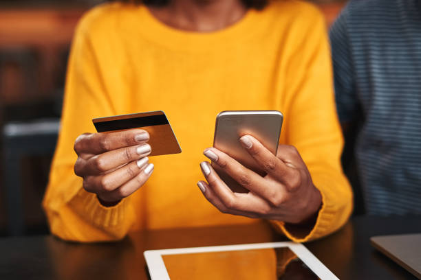 donna in un bar che fa shopping online con carta di credito - afro americano foto e immagini stock