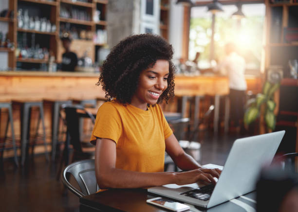 istock Young woman in cafe typing on laptop smiling 1159438487