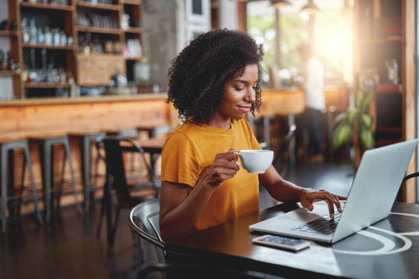 istock Young woman holding cup in in hand using laptop 1159439247