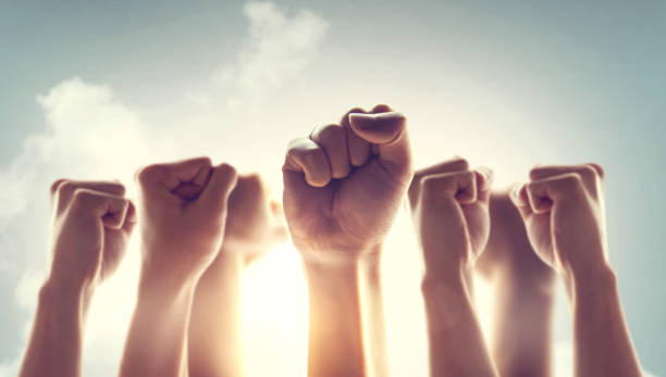istock Peoples raised fist air fighting and sunlight effect, Competition, teamwork concept. 1159439542