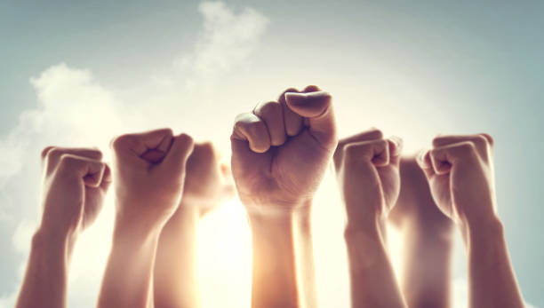 Peoples raised fist air fighting and sunlight effect, Competition, teamwork concept. Peoples raised fist air fighting and sunlight effect, Competition, teamwork concept. democracy stock pictures, royalty-free photos & images
