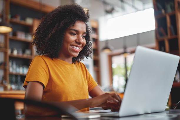 istock Happy young black woman using laptop in cafe 1159440493