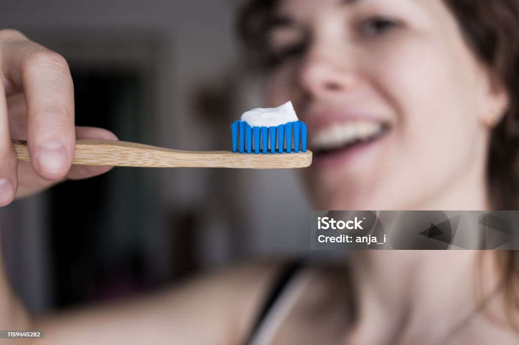 Woman holding a bamboo toothbrush with a toothpaste Toothbrush Stock Photo