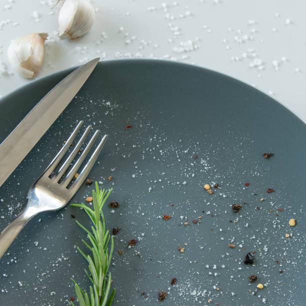 istock Grey empty ceramic plate with herbs knife and fork on salty white background. Minimal design. Space for text or menu 1159447691