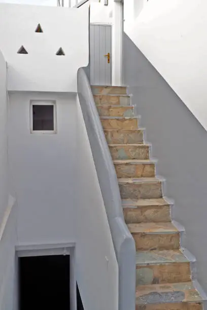 Photo of One of the charms of Mykonos, Greek island in the heart of the Cyclades, are its narrow staircases to access white houses with small flowered balconies touching almost above the cobblestone streets
